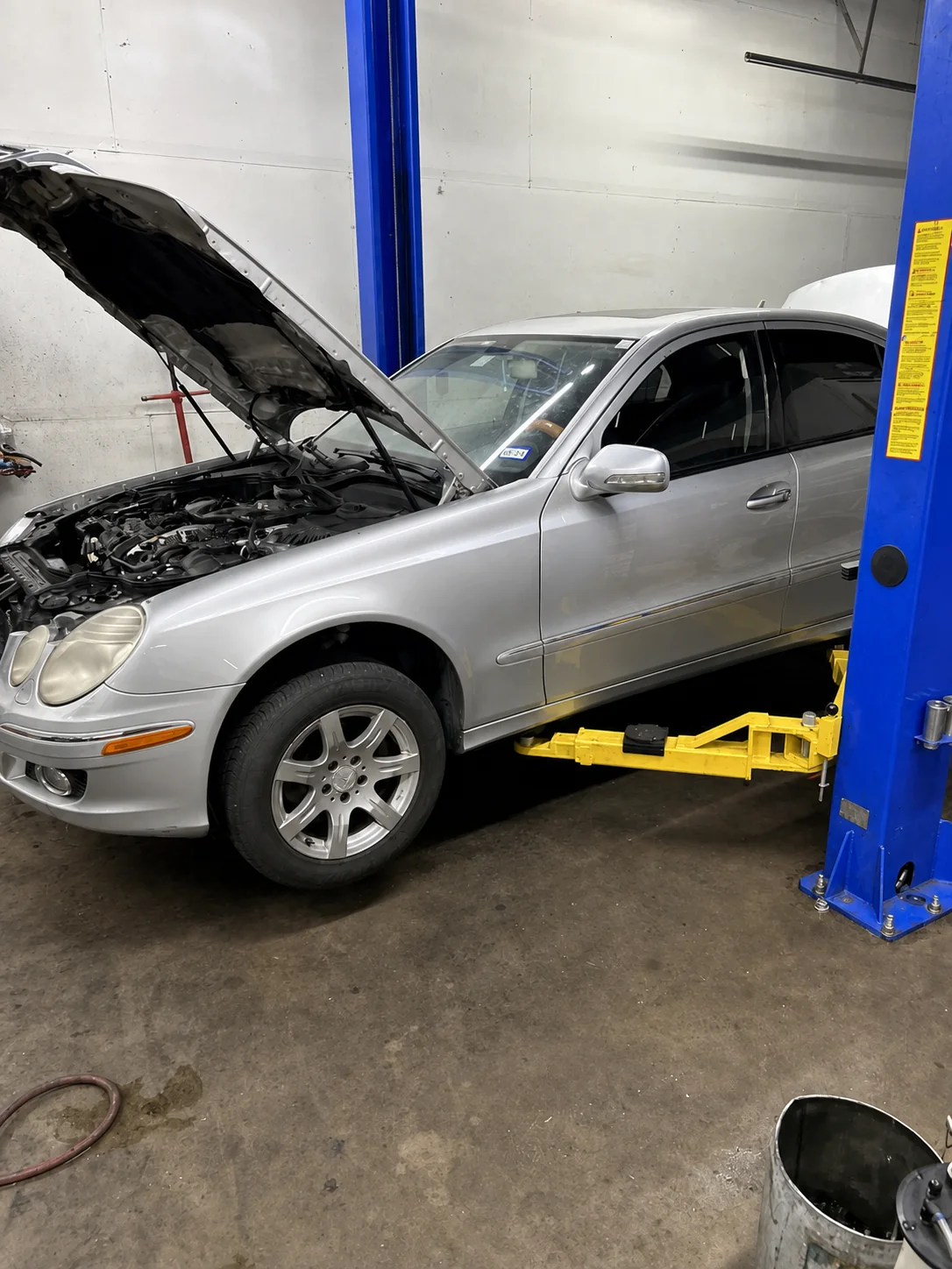 Silver Mercedes with its hood open on a two-post lift
